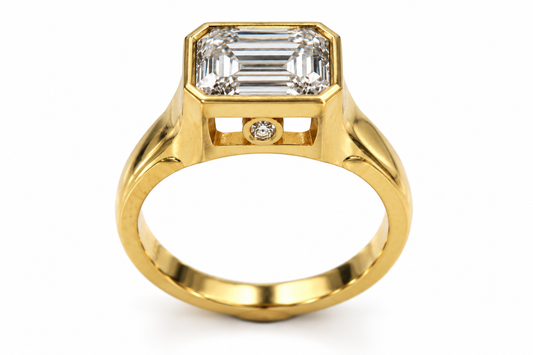 18ct yellow gold ring with an emerald-cut centre stone, shown on a white background